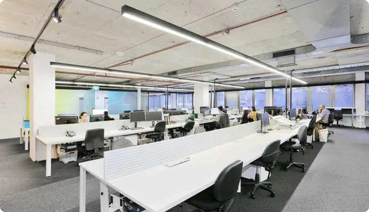 Bureau open space avec longues rangées de postes de travail et équipes au bureau