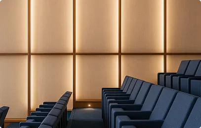 Reihe von blauen Kinosesseln in einem modernen, minimalistisch beleuchteten Raum mit warmen Paneelen an der Wand.