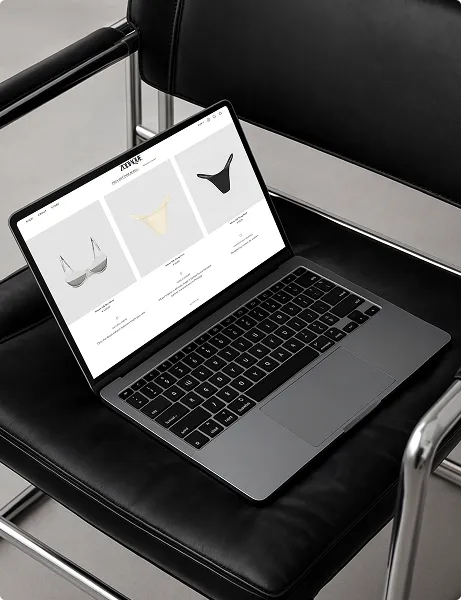 Laptop auf einem schwarzen Lederstuhl zeigt eine Webseite mit Unterwäscheprodukten.