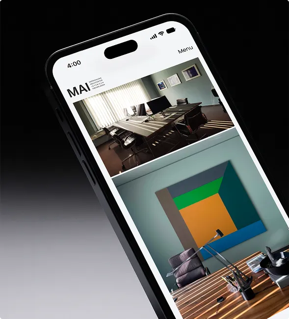 Smartphone displaying a website with photos of a modern office space featuring a conference table with chairs and a desk with a colorful geometric wall art.