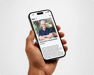 Hand hält ein Smartphone mit einem Profilbild und Text von Joachim Muscheid auf dem Bildschirm.