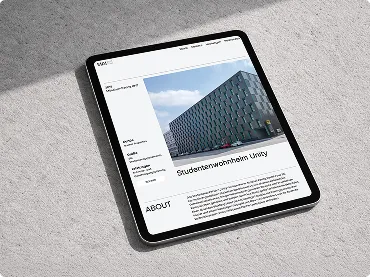 Tablet zeigt eine Webseite mit Foto eines modernen Gebäudes und Textüberschrift 'Studentenwohnheim Lizzy'.
