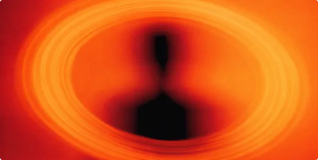 Aufnahme eines schwarzen Lochs mit heller, rot-orangefarbener Akkretionsscheibe.