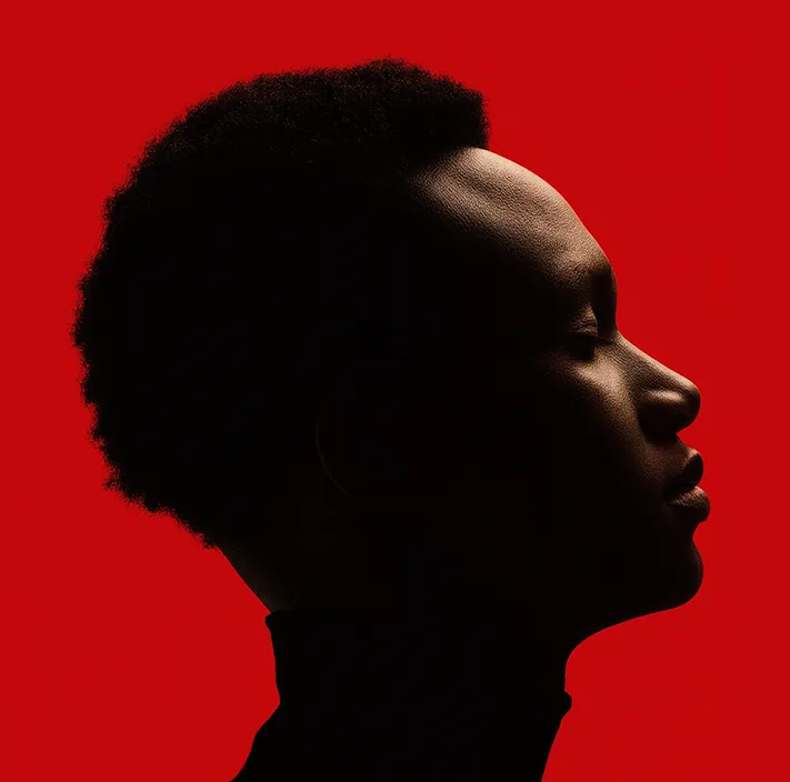 Seitenprofil eines nachdenklichen jungen Mannes mit geschlossenen Augen vor rotem Hintergrund.