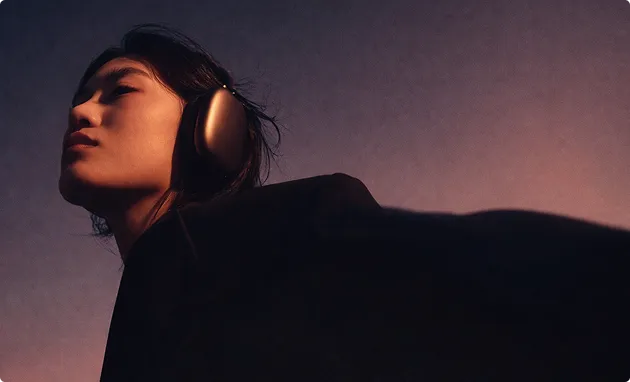 Frau mit geschlossenen Augen und Kopfhörern im dunklen Licht mit dunklem Hintergrund.