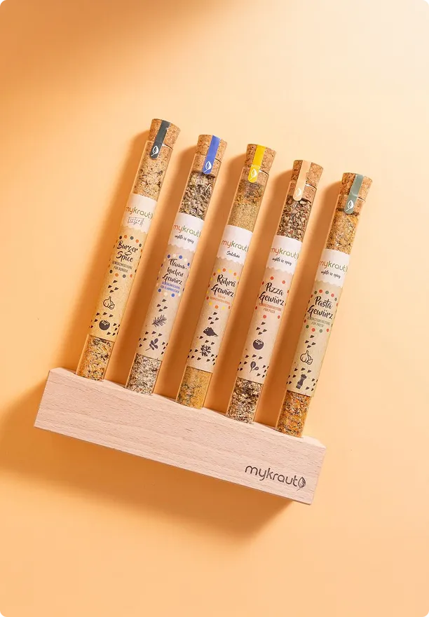 Fünf Gewürzproben in Glasröhrchen stehend auf einem Holzhalter mit dem Schriftzug mykraut.