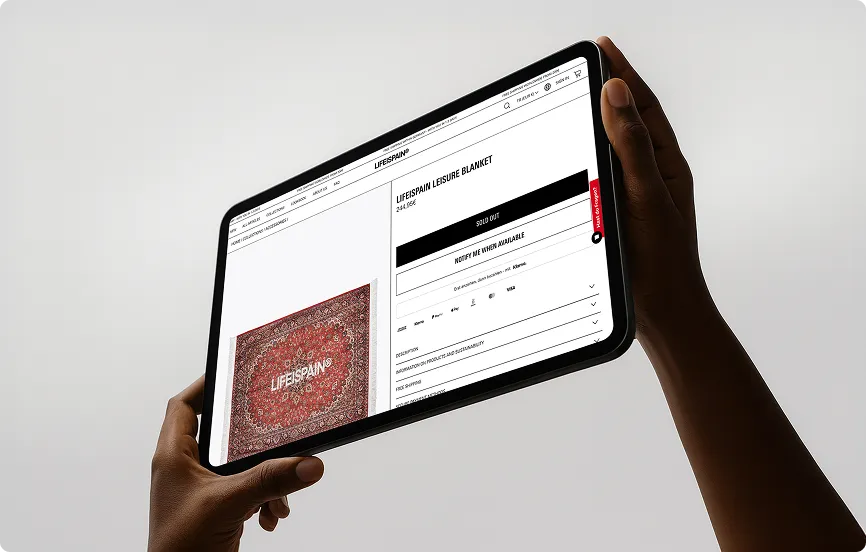 Person hält ein Tablet, das eine ausverkaufte Lebensdauer-Freizeitdecke mit rotem Muster zeigt.