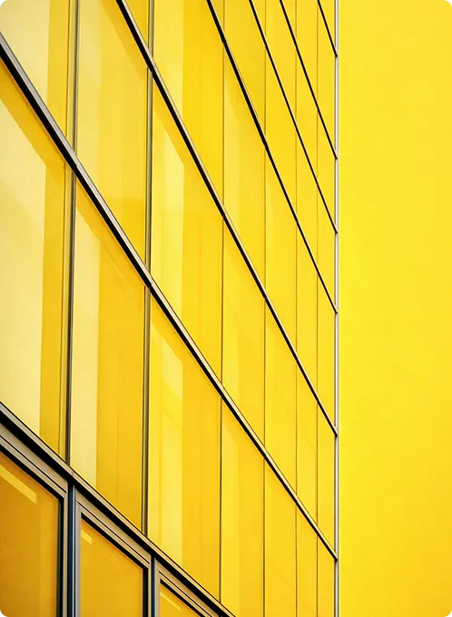 Fassade eines Gebäudes mit großen gelben Fensterfronten und einer gelben Wand.