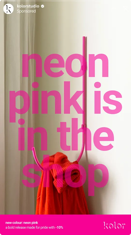 Neonpinkfarbener Haken an weißer Wand mit orangem Pullover, Text: Neon Pink ist im Shop, Werbung für neue neonpinke Farbe mit 10% Rabatt bei Kolorstudio.