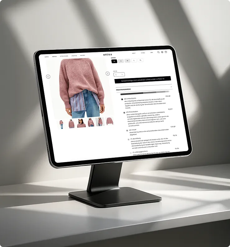 Tablet auf schwarzem Ständer zeigt eine Webseite mit einem Model, das einen rosa Pullover und Jeans trägt.
