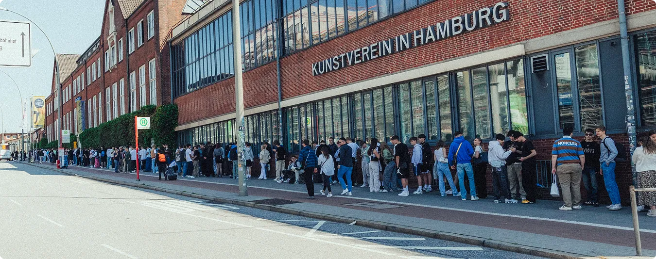 Lange Warteschlange von Menschen vor dem Kunstverein in Hamburg neben einem roten Backsteingebäude.