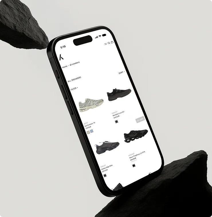 Smartphone mit geöffneter Webseite zum Online-Kauf von Sneakern, die Schwarz- und Grautöne zeigen.