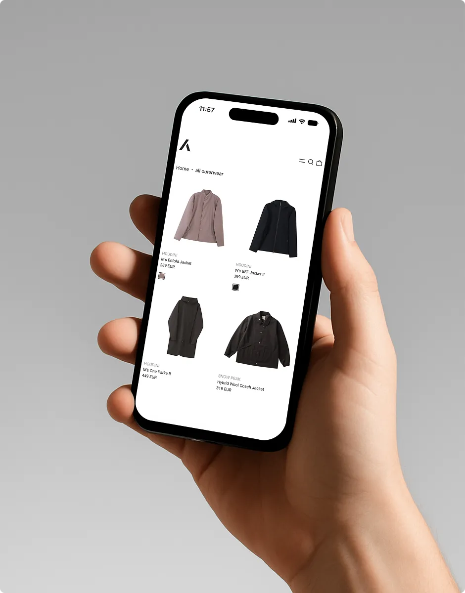 Hand hält ein Smartphone mit einer Online-Shop-Seite, die vier Jacken mit Preisen in Euro zeigt.