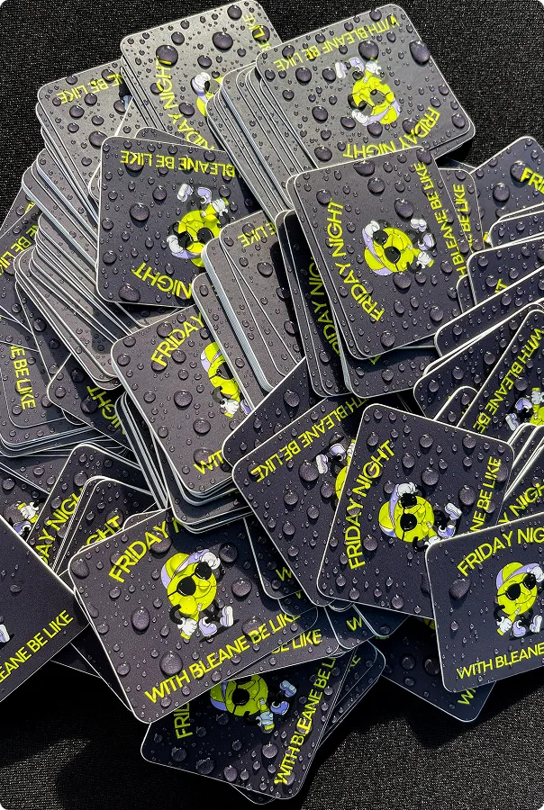 Viele aufeinander liegende schwarze Quadratische Karten mit Wassertröpfchen, darauf ein gelbes lachendes Emoji mit Sonnenbrille und Kopfhörern, Text: Friday Night with Bleane be like.