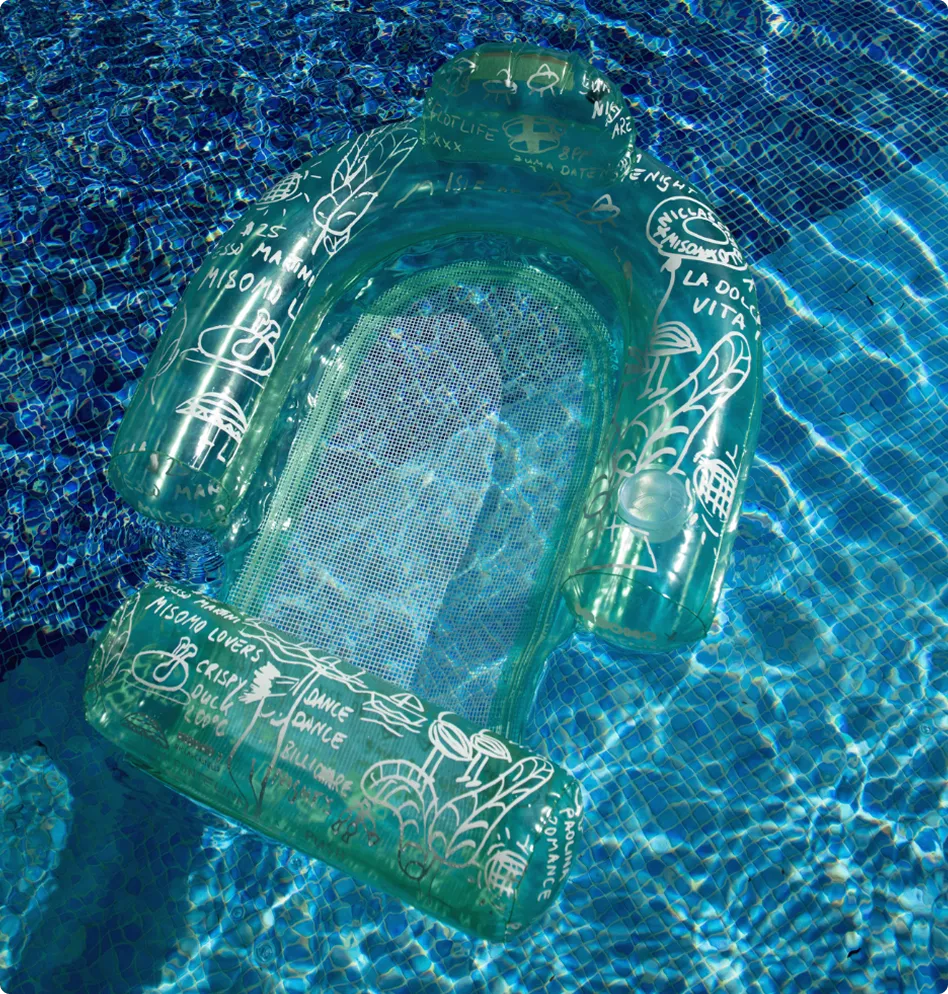 Grüner aufblasbarer Poolstuhl mit weißen Zeichnungen schwimmt in blau gekacheltem Wasser.