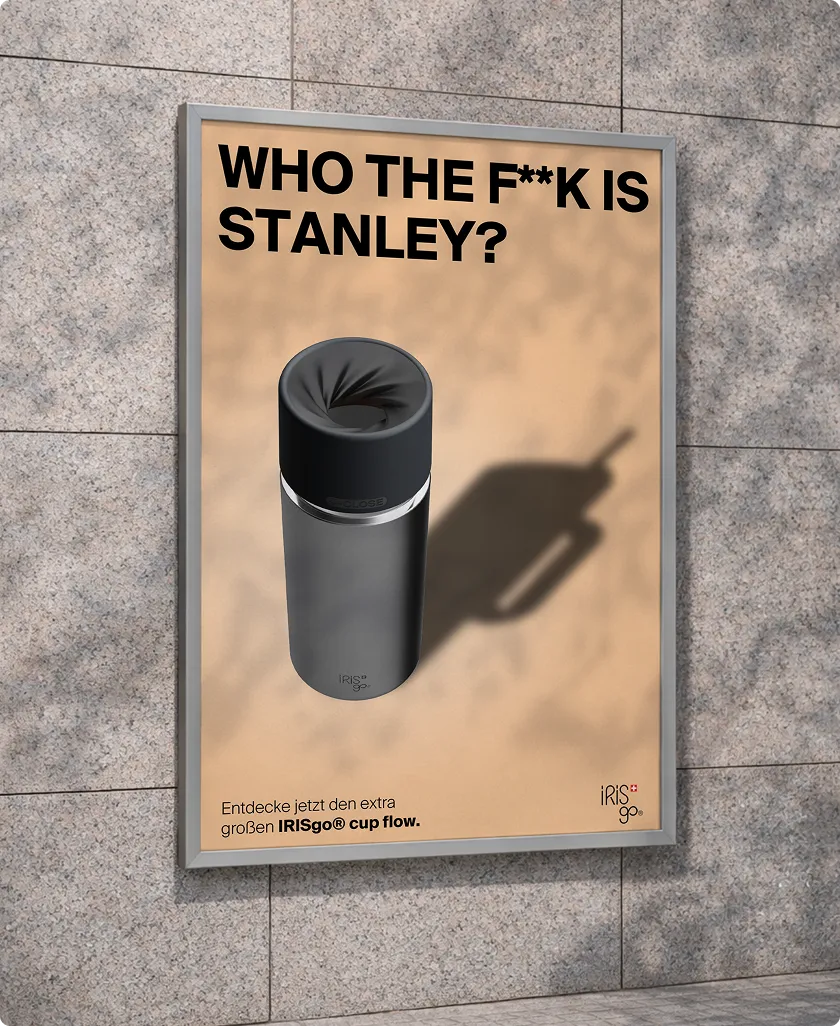 Who the hell is Stanley? Poster with a grey IrisGo Cup Flow drinking bottle against a beige background on a stone wall.