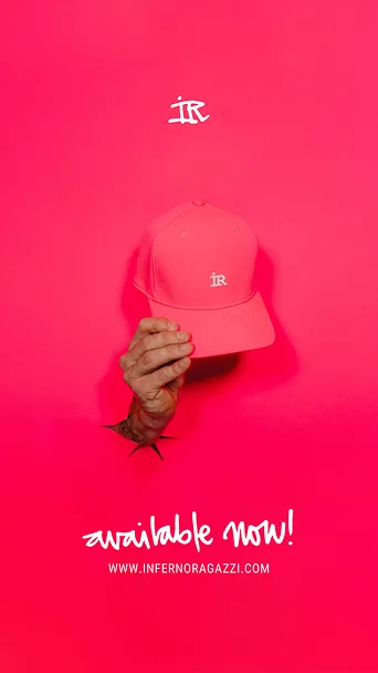 Hand hält eine rosa Baseballkappe mit weißem IR-Logo vor rosa Hintergrund, darunter Text 'available now!' und Website www.infernoragazzi.com.