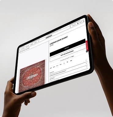 Person hält ein Tablet mit geöffneter Webseite, die Produktinformationen und ein Bild eines roten Teppichs zeigt.