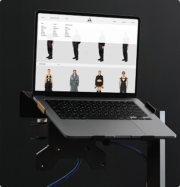 Laptop auf einem schwarzen Ständer zeigt auf dem Bildschirm eine Webseite mit Modekleidung und einer Navigationsleiste.