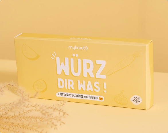 Gelbe Verpackung von mykraut mit weißer Schrift 'Würz dir was!' und Aufschrift 'Ausgewählte Gewürze nur für dich', 100% plastikfrei.