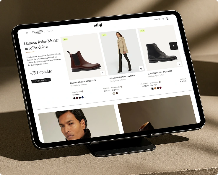 Tablet zeigt eine Webseite mit Damenmode, darunter brauner Chelsea Boot aus Kalbsleder, Shearling Coat in Lammskin und schwarzer Schnürboot.