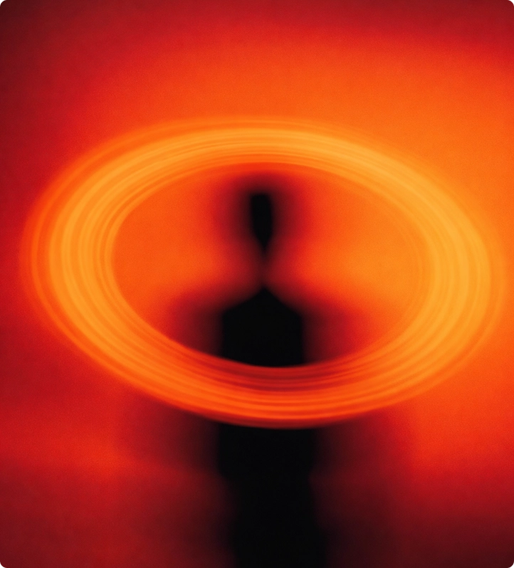 Schwarze Silhouette einer Person vor einem leuchtend orange-roten Hintergrund mit kreisförmigem Licht an der Brusthöhe.