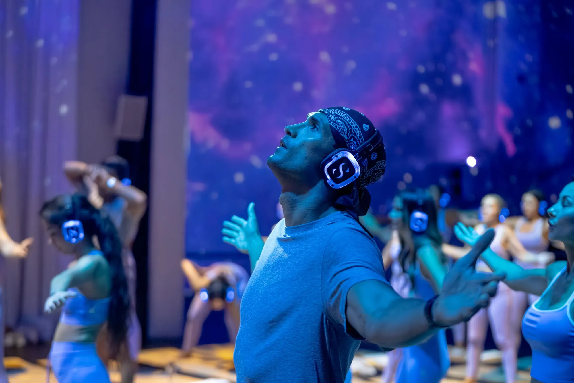A guest looks up into blue projections mid-class at TODA, Dubai
