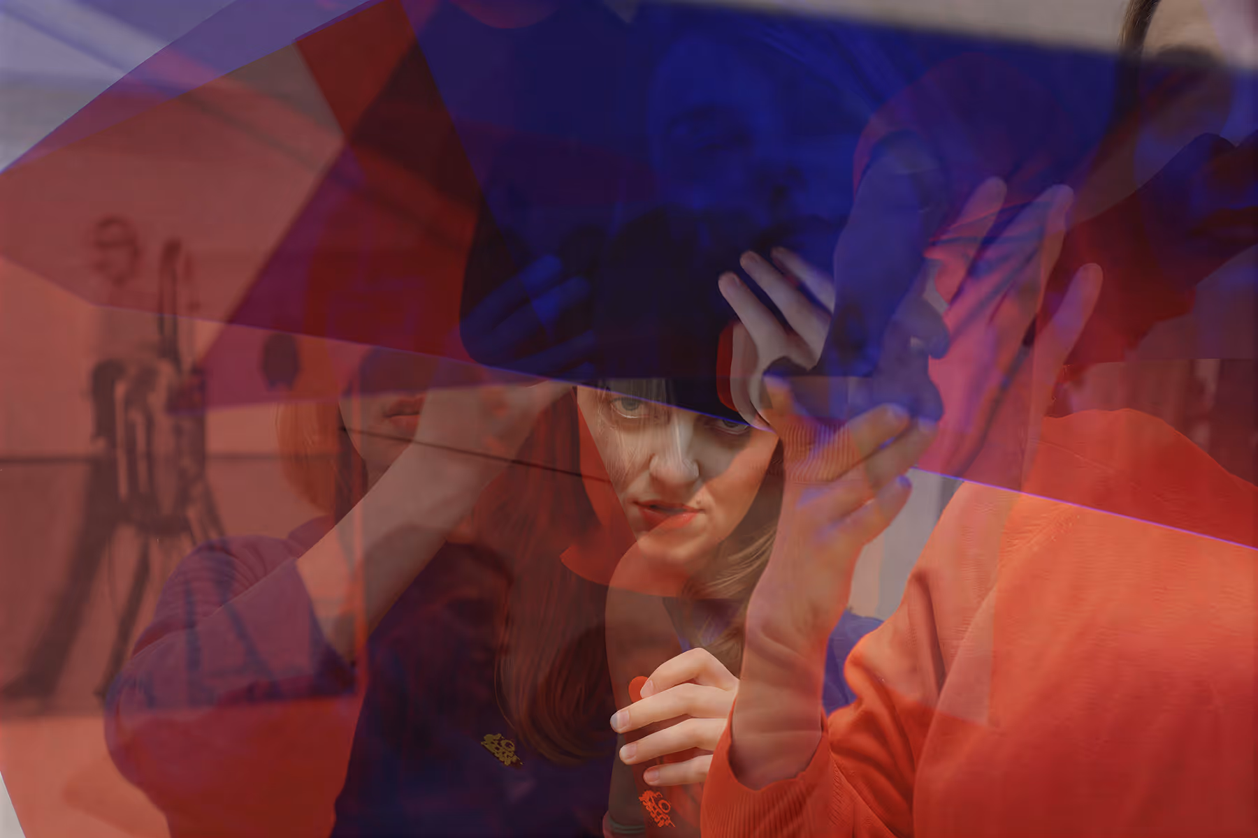 Double exposure image of a woman adjusting a black hat with her hands, layered with red and blue tinted hands and faces.