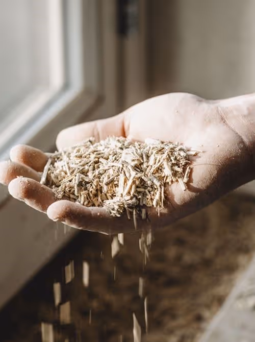Een hand houdt houtsnippers vallen