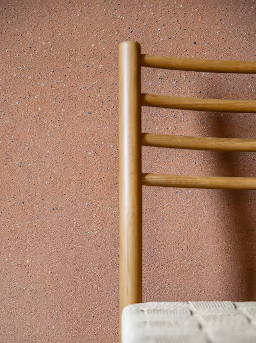 Twee arbeiders in een werkplaats die houten stukjes op een tafel rangschikken, met een geometrisch patroon op de vloer voor hen.