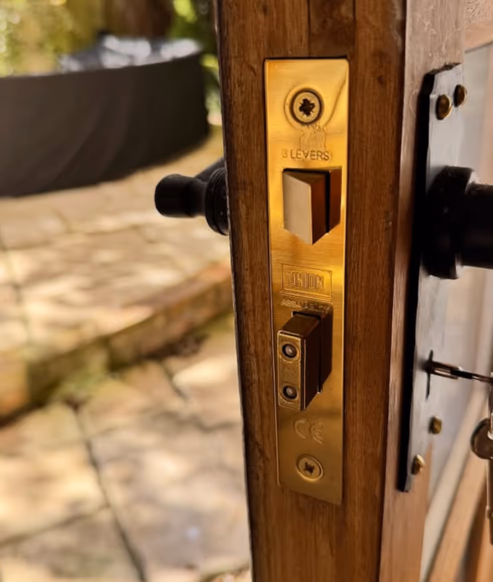 Close-up of a brass door lock mechanism on a wooden door, showing the latch and keyhole with a key inserted.