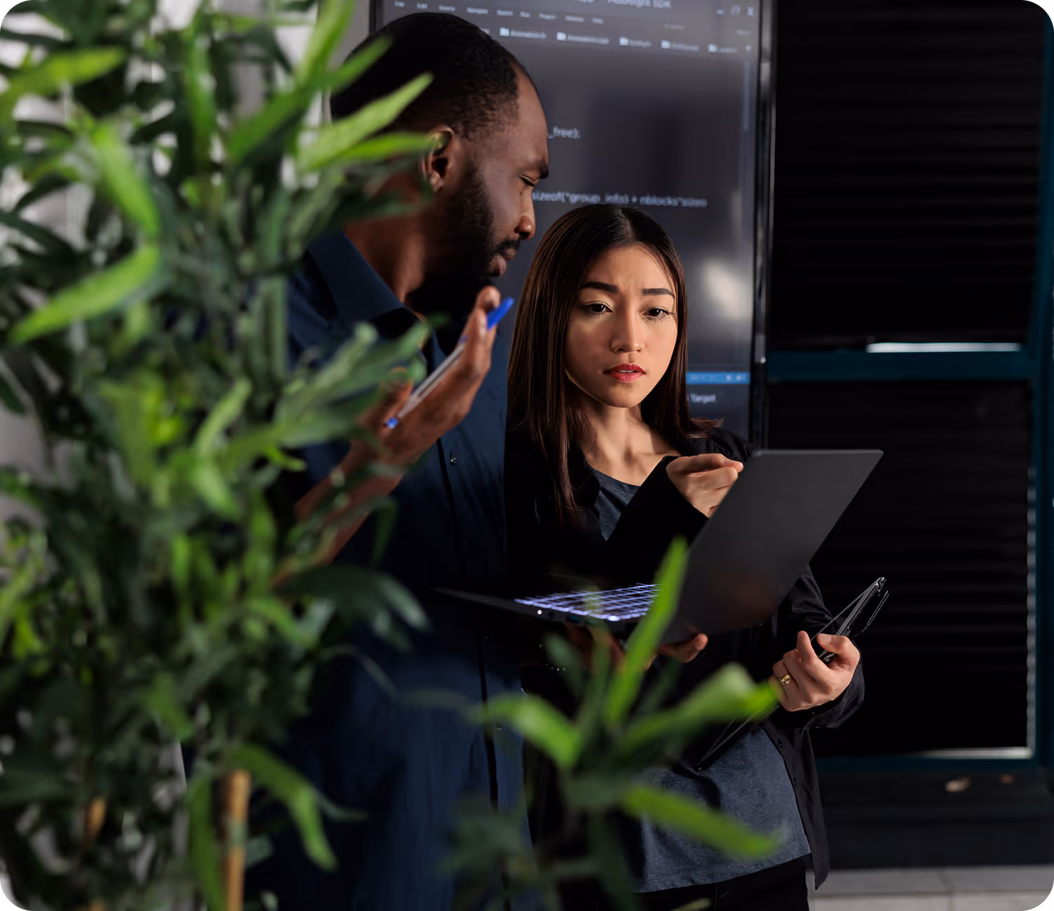 Three business professionals in a bright, modern office lounge having a discussion with digital devices.