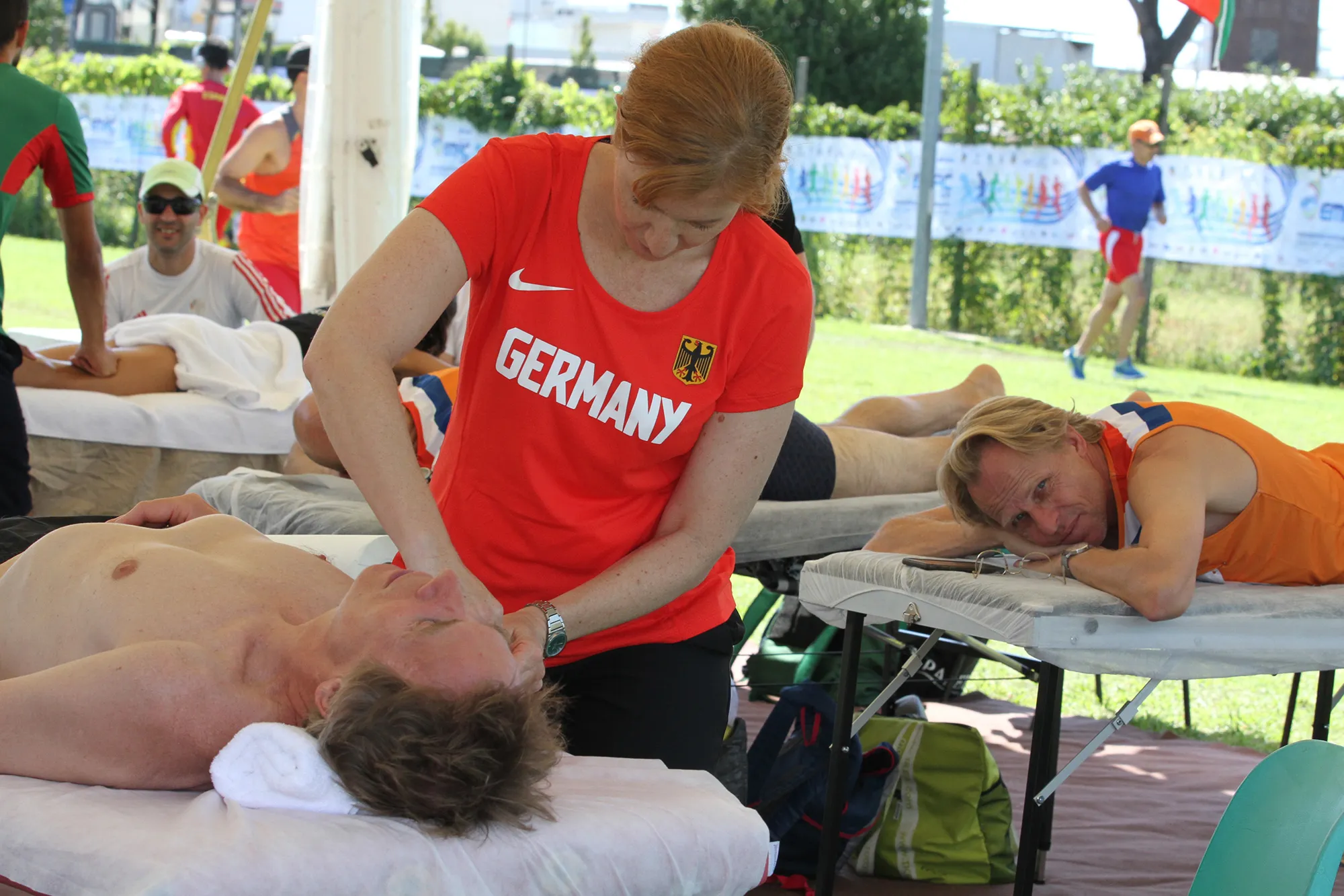 Jessica Mathiak betreut Athleten bei einer Sportveranstaltung im Deutschland-Trikot als Physiotherapeutin