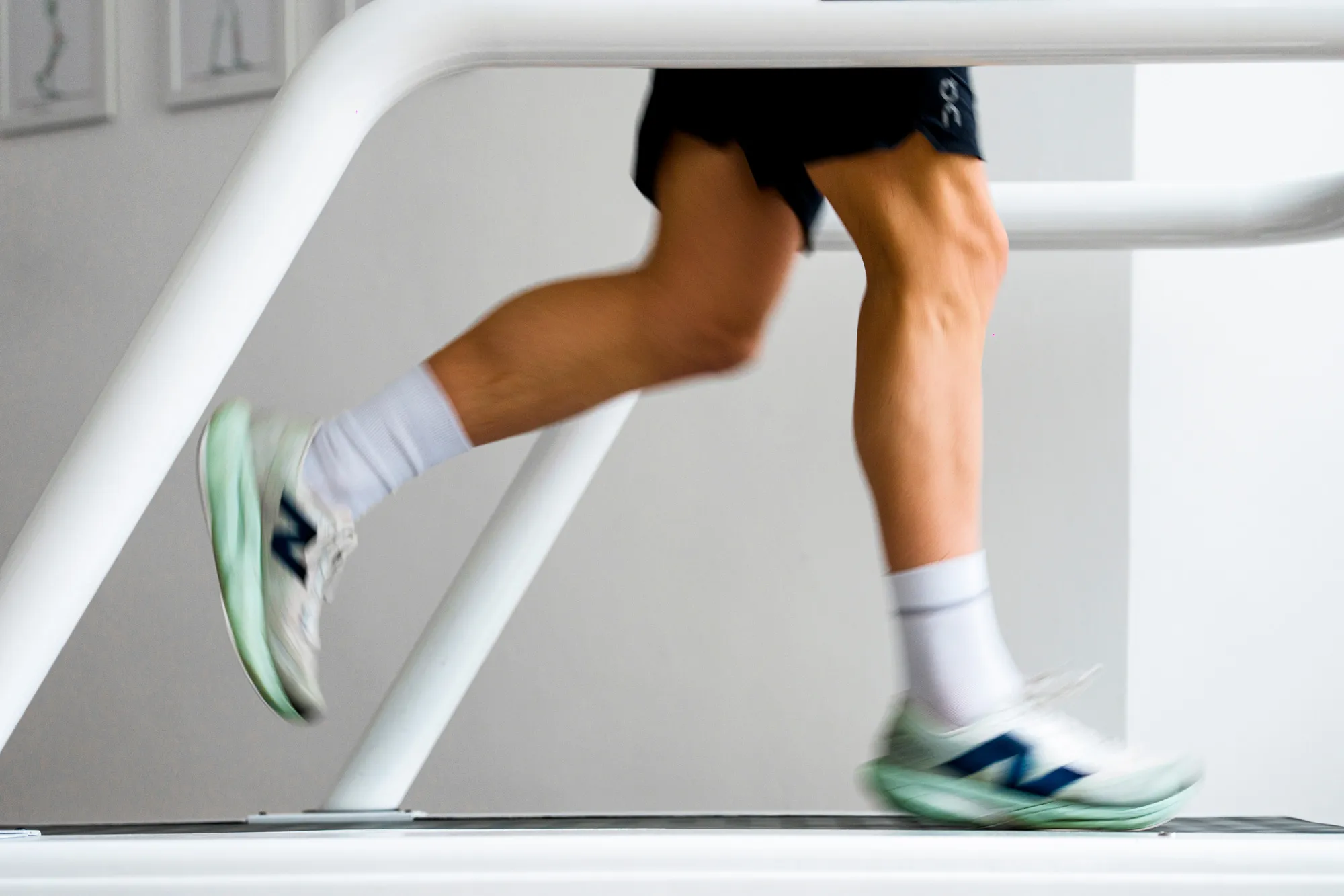 Nahaufnahme von Beinen auf einem Laufband in Bewegung, mit grün-weißen Sportschuhen und weißen Socken