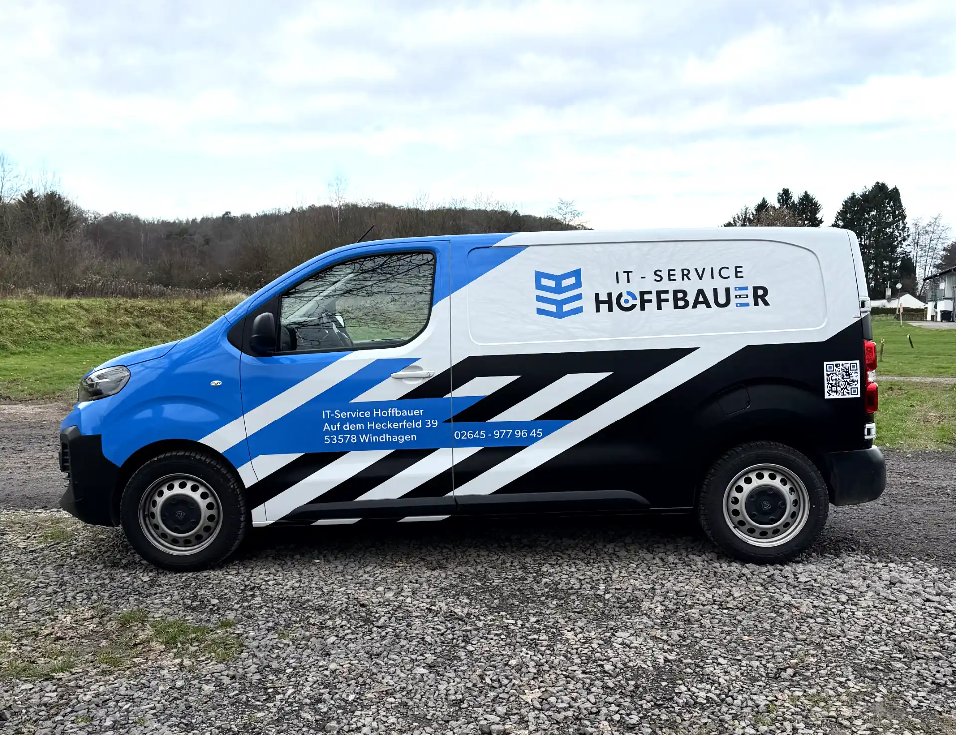 Dienstfahrzeug mit blau-schwarzem Design und Aufschrift IT-Service Hoffbauer, Adresse und Telefonnummer auf der Seite.