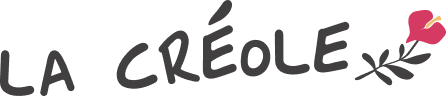 Texte « LA CRÉOLE » avec une petite fleur rose et jaune à droite.