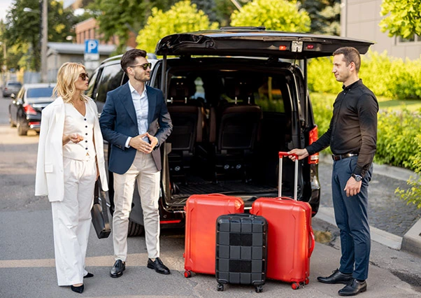 Un groupe de trois personnes se tient à côté d'une voiture chargée de bagages, prêt à partir.