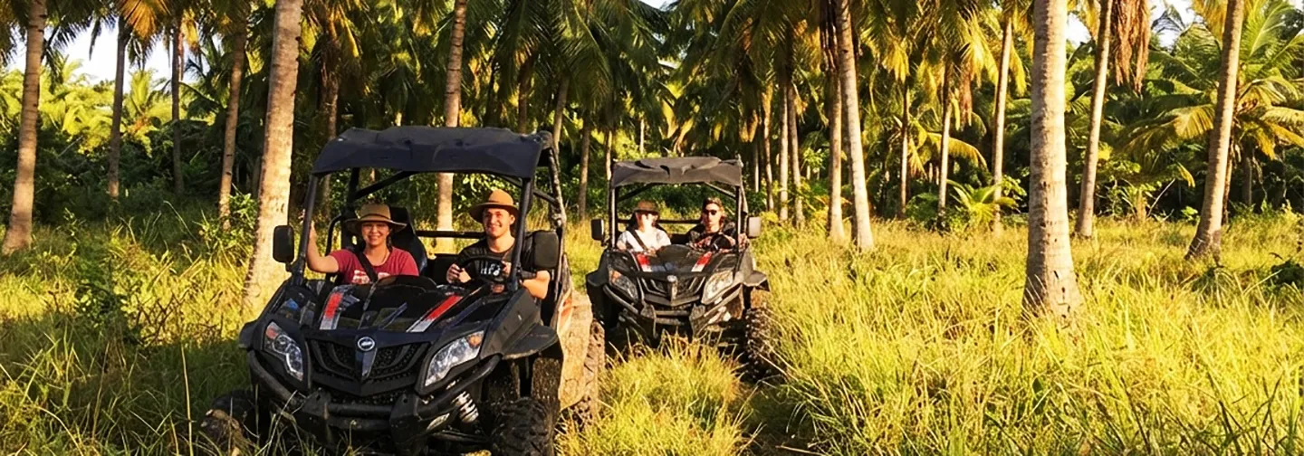 Clients souriants pilotant des buggies tout-terrain à travers une palmeraie tropicale luxuriante, une activité aventure proposée par La Créole Beach Hôtel & Spa.