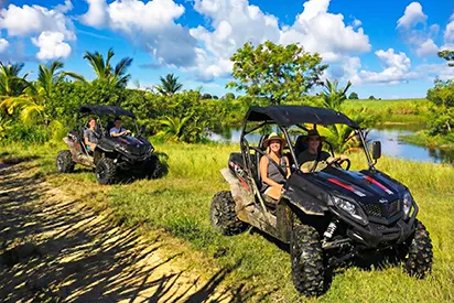 Deux buggies tout-terrain explorant les paysages sauvages de la Guadeloupe sous un ciel bleu, une aventure signée La Créole Beach Hôtel & Spa.