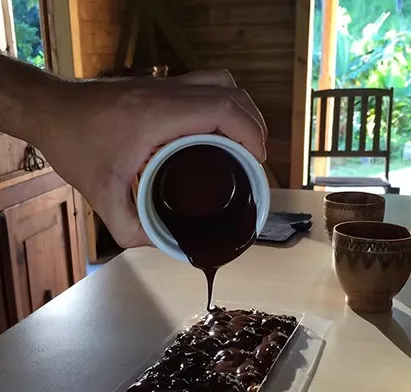 Versage de chocolat fondu dans un moule lors d'une démonstration culinaire artisanale à La Créole Beach Hôtel & Spa.