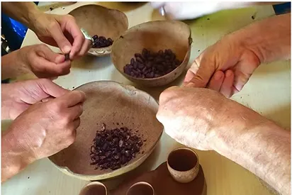 Mains de participants décortiquant des fèves de cacao lors d'un atelier artisanal à La Créole Beach Hôtel & Spa, Guadeloupe.