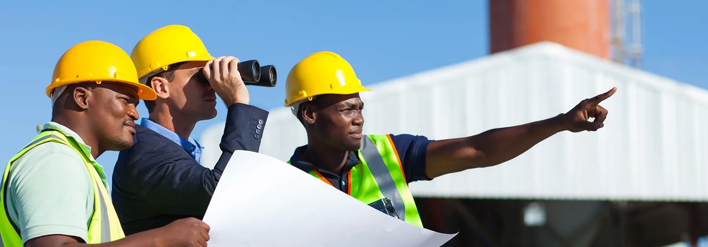Ingénieurs et techniciens en casques de sécurité examinant des plans lors d'une visite industrielle organisée par La Créole Beach Hôtel & Spa.