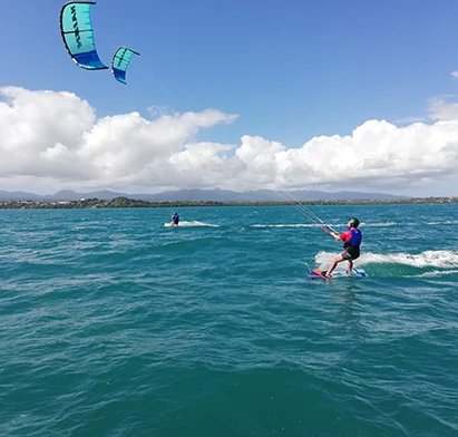 Kitesurf en mer face à La Créole Beach Hôtel & Spa sous un ciel nuageux.