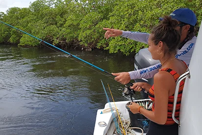 Une femme et son guide pratiquant la pêche en mer près des mangroves, une activité proposée par La Créole Beach Hôtel & Spa.