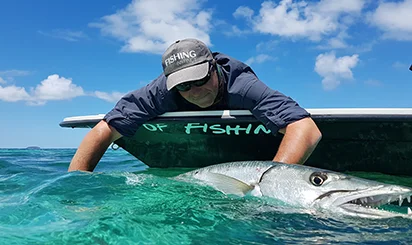 Pêcheur remettant à l'eau un barracuda en Guadeloupe, activité partenaire de La Créole Beach Hôtel & Spa