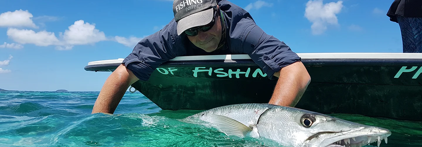 Pêcheur remettant à l'eau un barracuda en Guadeloupe, activité partenaire de La Créole Beach Hôtel & Spa
