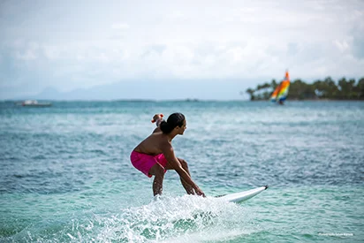 Homme pratiquant le surf électrique dans les eaux turquoise devant La Créole Beach Hôtel & Spa.