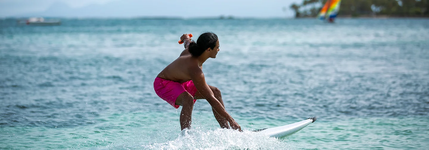 Homme pratiquant le surf électrique dans les eaux turquoise devant La Créole Beach Hôtel & Spa.