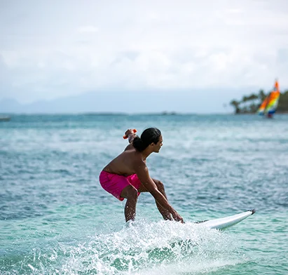 Homme pratiquant le surf électrique dans les eaux turquoise devant La Créole Beach Hôtel & Spa.