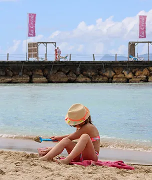 Petit fille qui joue dans le sable sur la plage de la Créole Beach en guadeloupe